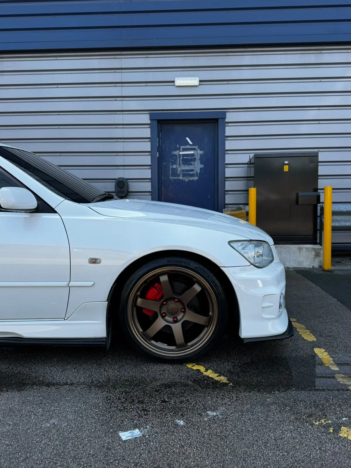 Bronze alloy and red caliper on a freshly washed white Lexus IS200