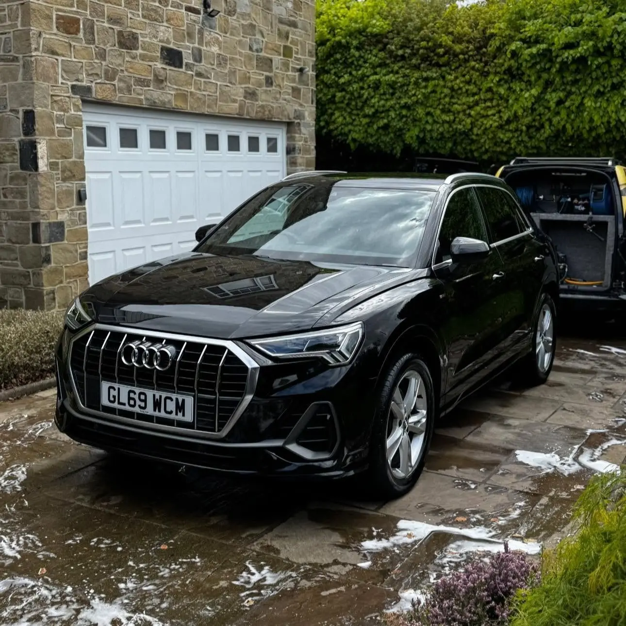 Black Audi Q3 covered in snow foam on a customer driveway