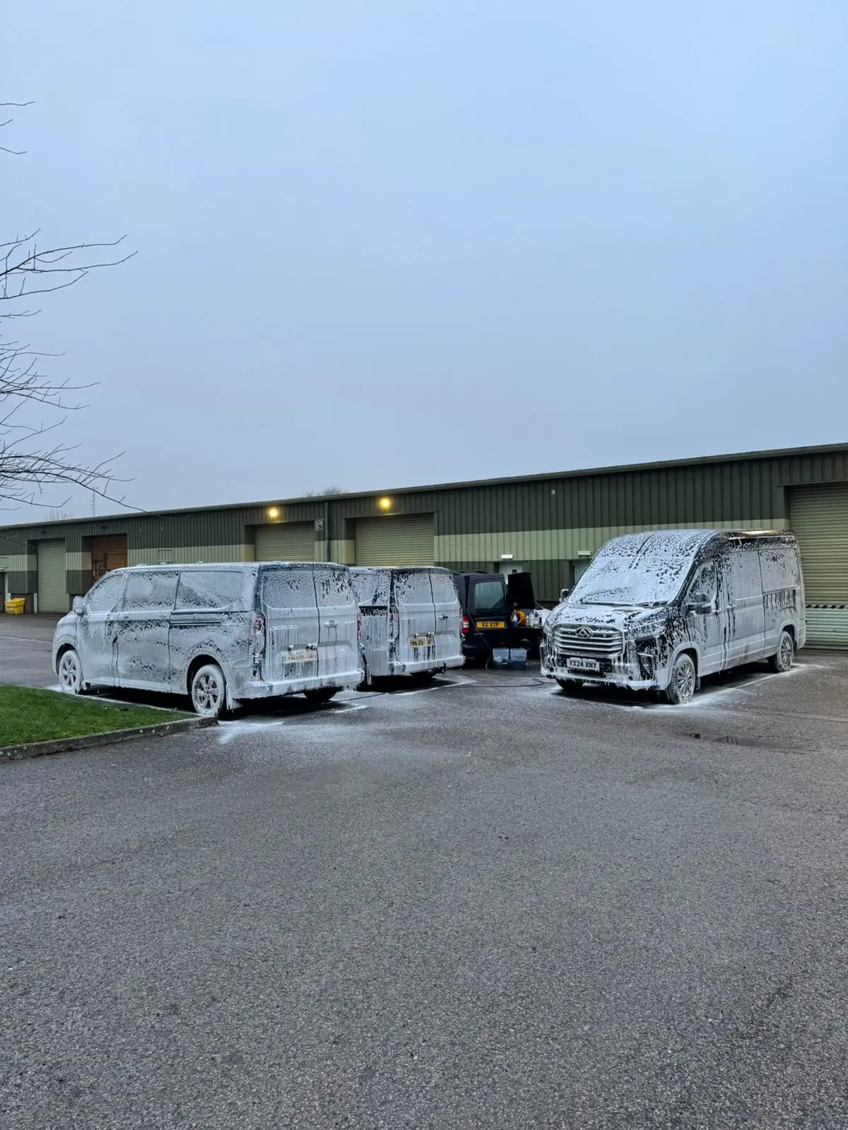 Three commercial vans foamed up for a fleet wash on an industrial estate