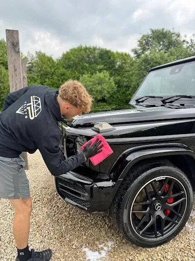 TP Car Care detailer hand-drying a black 4x4 on a customer's drive